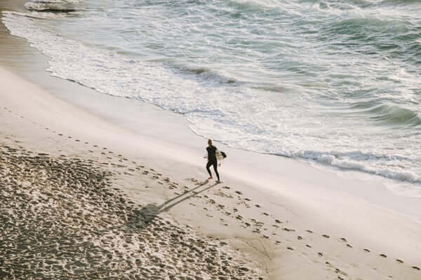 Person walking on a beach with footprints in the sand, symbolizing living by personal convictions and embracing individuality.