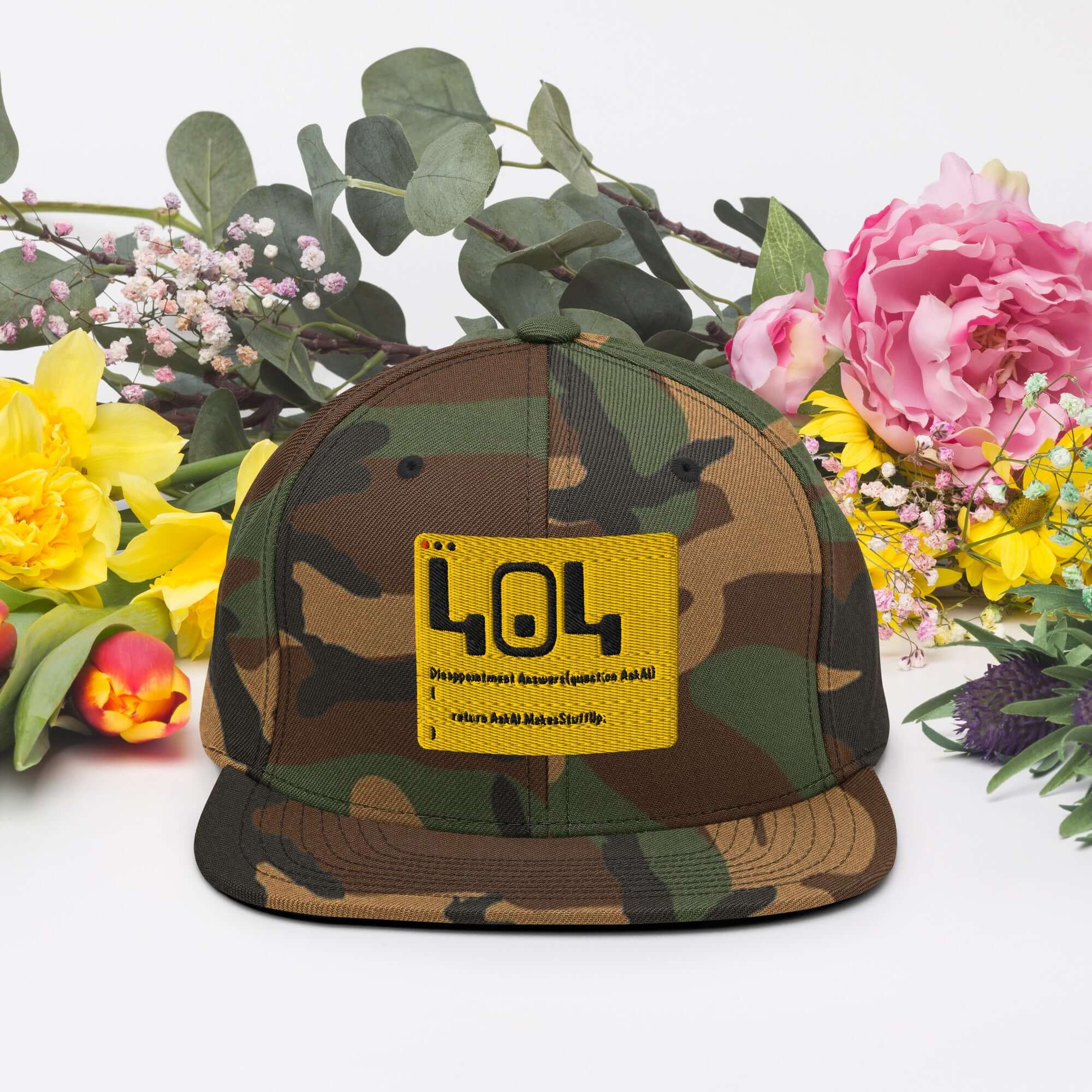 Camouflage 404 Disappointment Hat with yellow patch amidst flowers, ideal for developers seeking humor in tech mishaps.