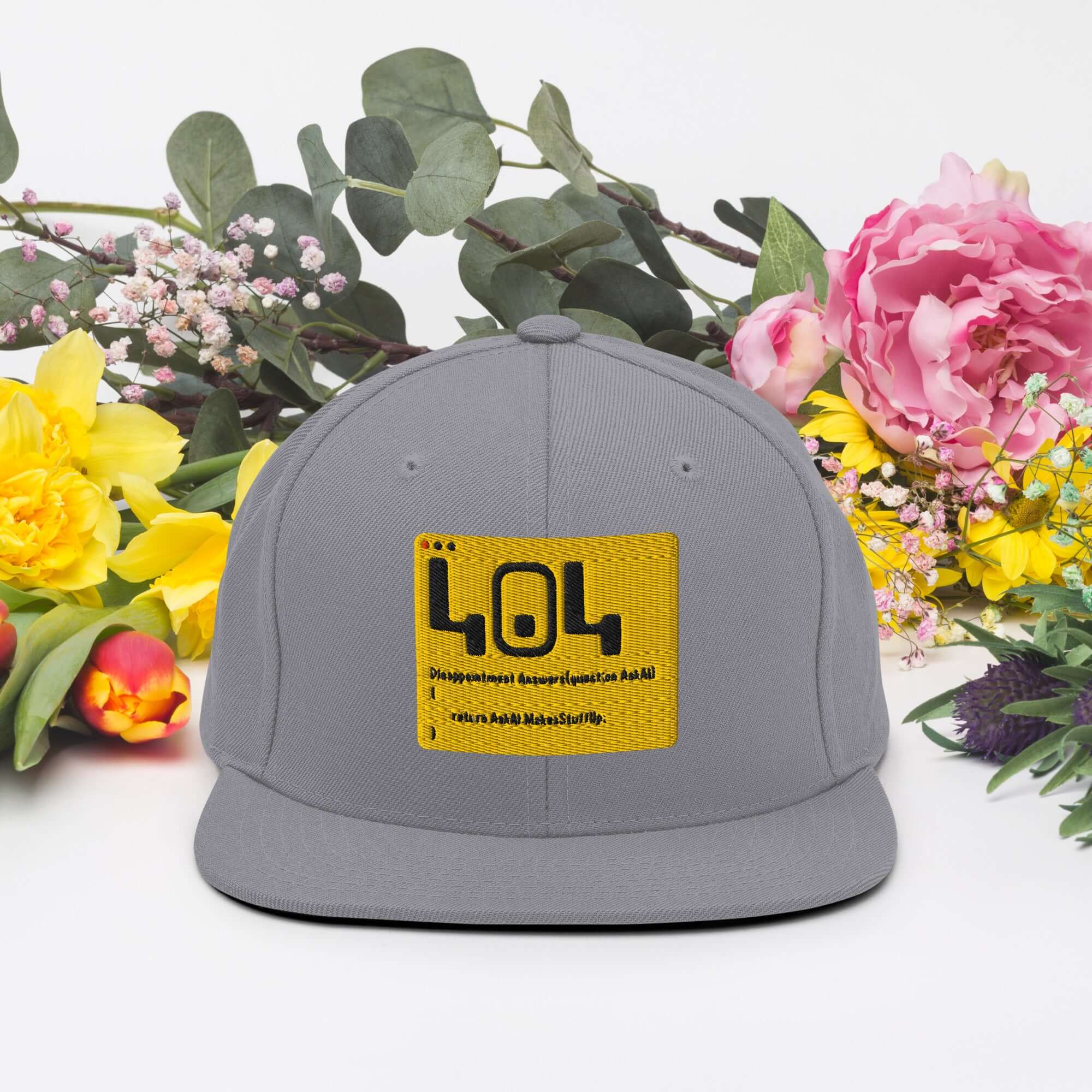 Gray 404 error snapback hat with yellow patch, surrounded by colorful flowers, perfect for developer humor and tech enthusiasts.