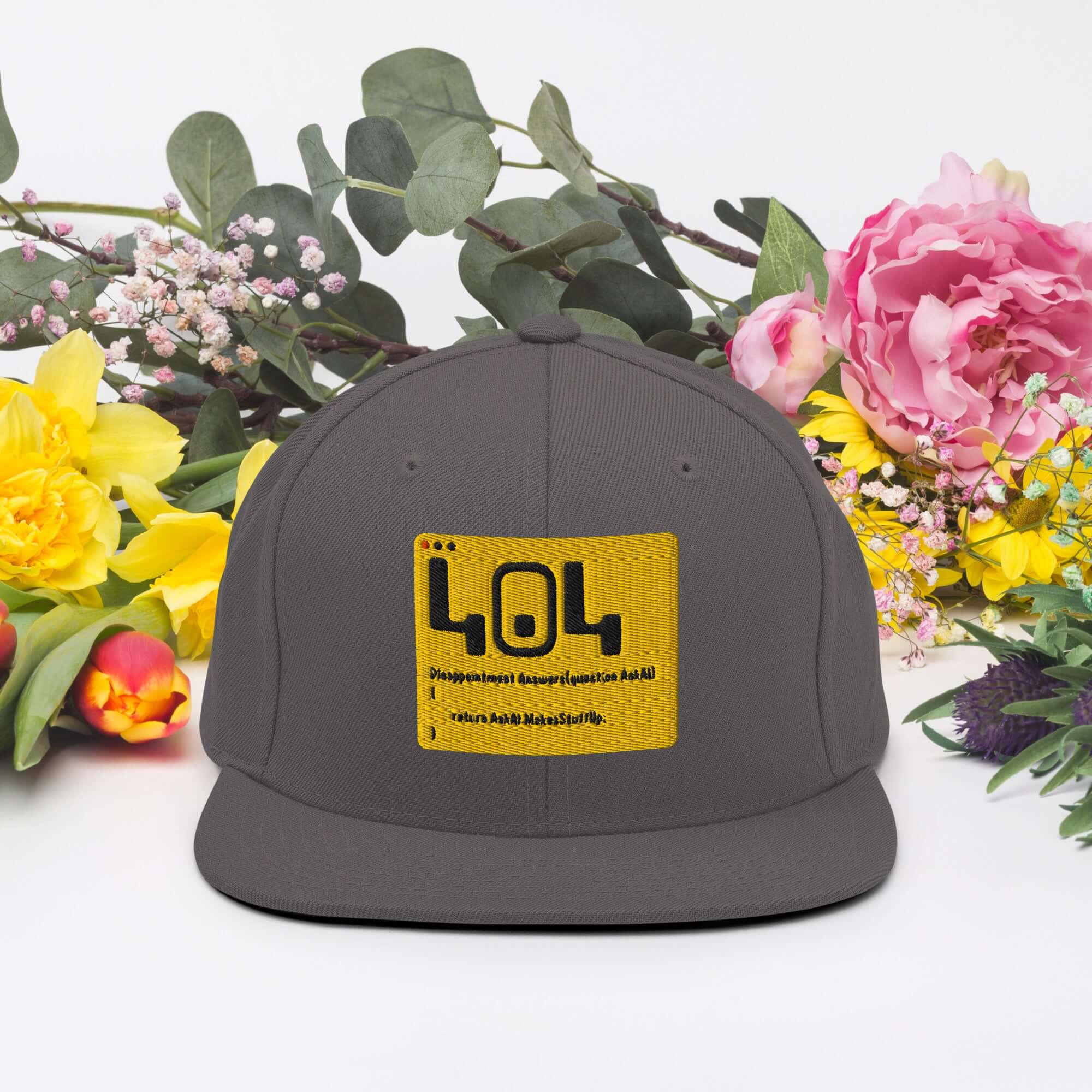 Gray 404 Error Code Snapback Hat with yellow patch, surrounded by colorful flowers, offering humorous developer headwear.