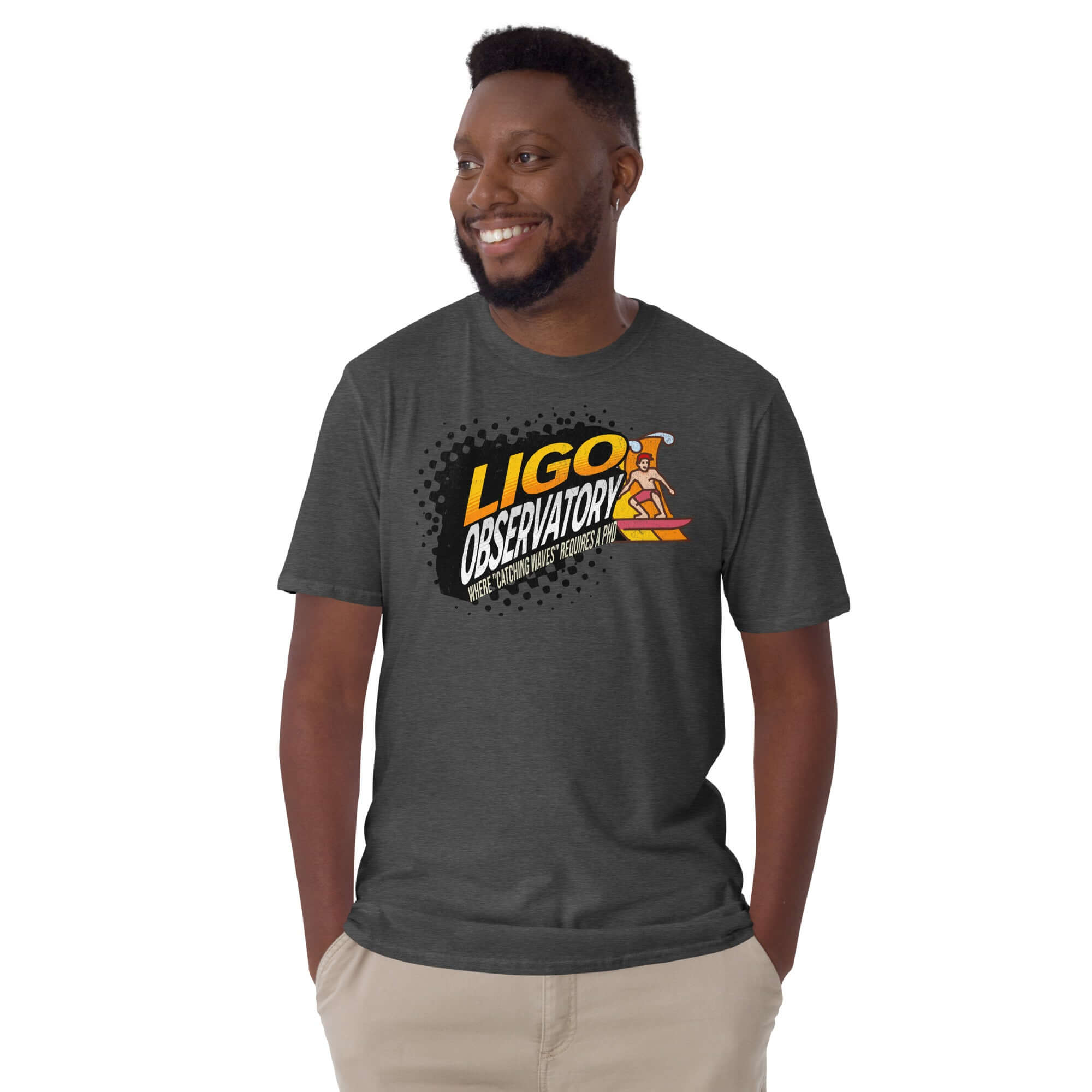Person wearing a charcoal LIGO Observatory T-shirt with vibrant gradient lettering, smiles while showcasing scientific surfwear style.