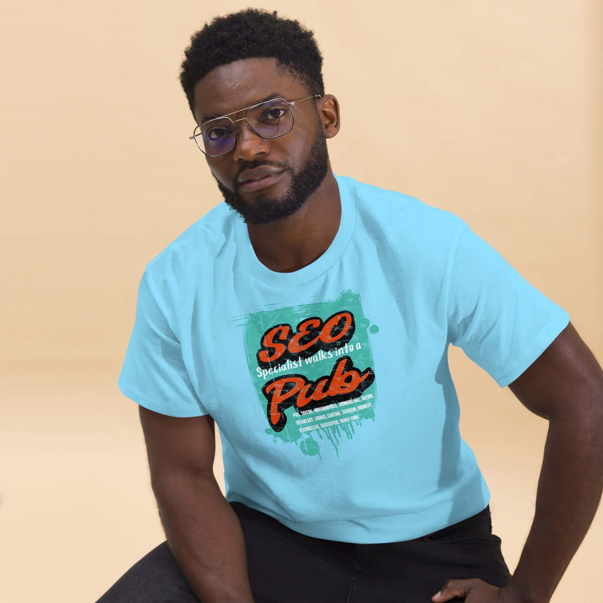 Man wearing 'SEO Specialist Walks Into a Pub' t-shirt, showcasing digital marketing humor with a relaxed pose against a neutral background.